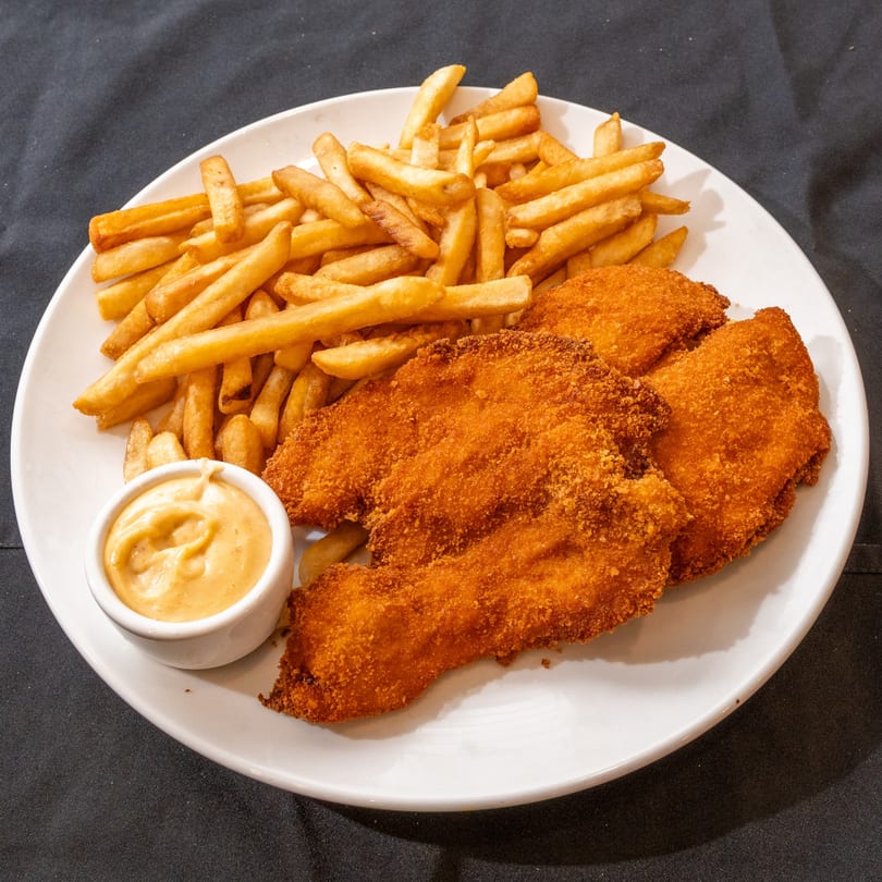 Crispy breaded chicken schnitzel with golden french fries and a side of dipping sauce.